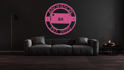 a living room with a black couch and a pink logo on the wall